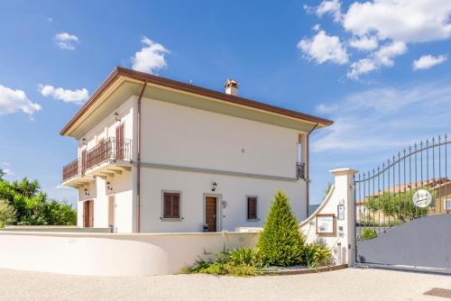 a small white house with a balcony and a fence at TENUTA FOGLIANI Resort & Natural Spa in Visciano