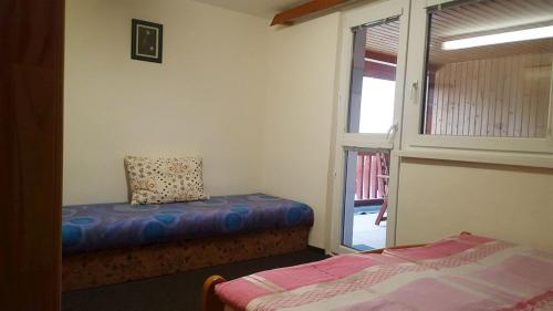 a room with a bed and a window with a pillow at Chata Marta in Liptovské Kľačany