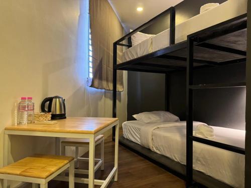 Pokój z biurkiem, łóżkiem piętrowym i stołem w obiekcie The Hive Hotel w Siem Reap