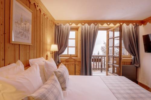 een slaapkamer met een groot bed en een raam bij La Ferme du Golf in Megève