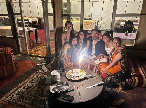 a group of people sitting around a table with a birthday cake at Exceptional Luxury Camp in Merzouga