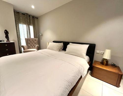 a bedroom with a large white bed and a chair at Forest View Apartments in Kololi