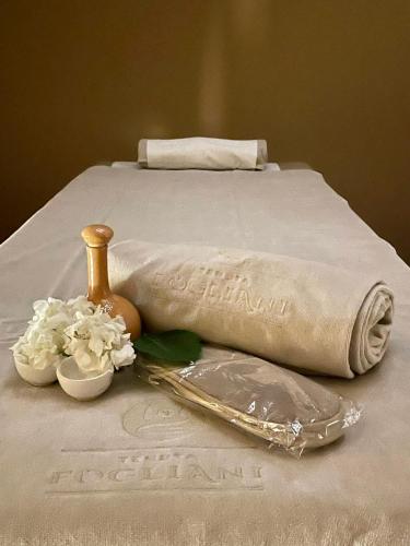 a bed with a towel and flowers on it at TENUTA FOGLIANI Resort & Natural Spa in Visciano