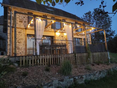 a log home with a fence and lights at Domaine de la Clauzade in Saint-Germain-les-Vergnes