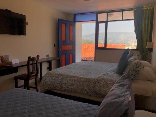 a bedroom with a bed and a desk and a window at Hotel Cabañas San Cayetano in Paipa