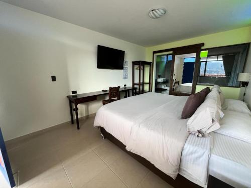 a bedroom with a bed and a desk and a television at Hotel Cabañas San Cayetano in Paipa