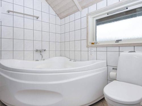 a white bathroom with a tub and a toilet at 9 person holiday home in Hemmet in Falen