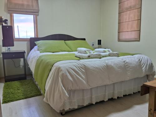 um quarto com uma cama com lençóis e almofadas verdes em Cabañas Frange em Puerto Natales