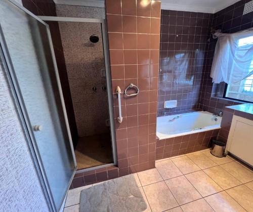 een badkamer met een douche, een bad en een wastafel bij Honeyhills Excellence Resorts D in Roodepoort
