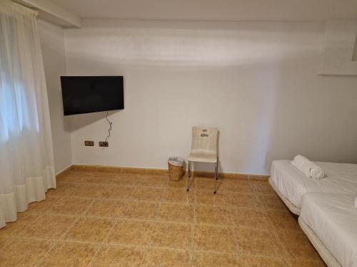ein Wohnzimmer mit einem Sofa und einem TV an der Wand in der Unterkunft Pensión Aussie II in San Sebastián