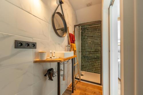 ein Bad mit einem Waschbecken und einem Wandspiegel in der Unterkunft La Loge Bed & Breakfast 
