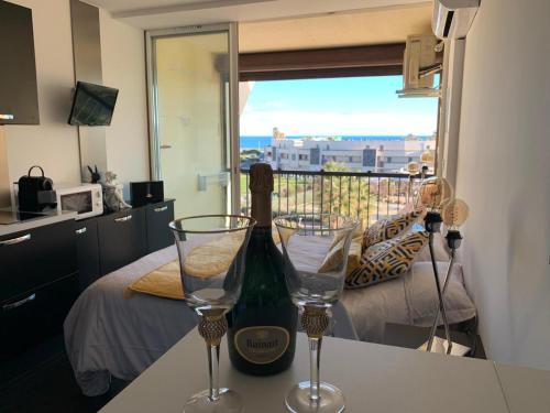 - une bouteille de vin assise sur un comptoir avec deux verres dans l'établissement BAGATELLE NATURISTE HELIOPOLIS clim ascenseur vue mer parking privé, au Cap d'Agde