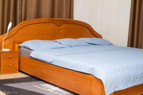 a bed with a wooden headboard and a night stand at Luxury Apartments in Kumasi