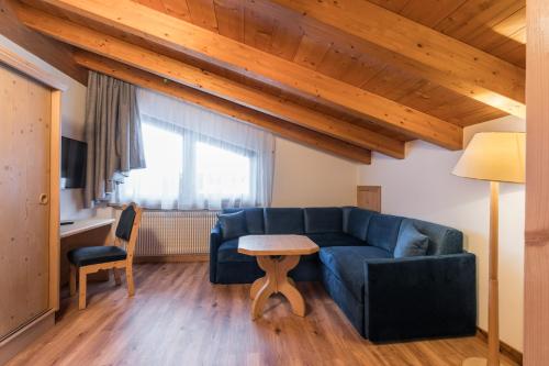 a living room with a blue couch and a table at Hotel Armin in Selva di Val Gardena