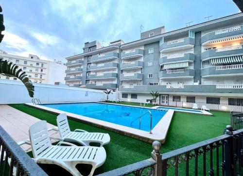 een zwembad met 2 stoelen en een gebouw bij Exclusive Penthouse Pool & Beach - Lovely for families - Los Pinos Residential in El Campello