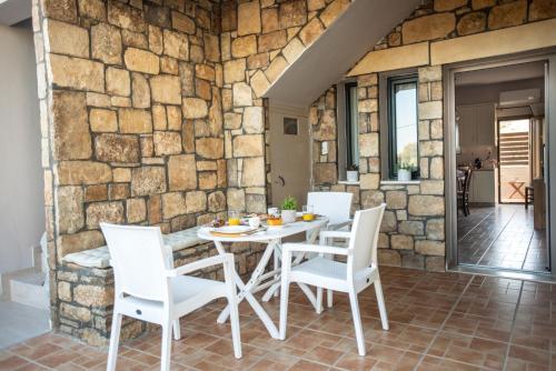 a stone walled patio with a white table and chairs at Gifel - Luxury apartment in Kalamaki Heraklion