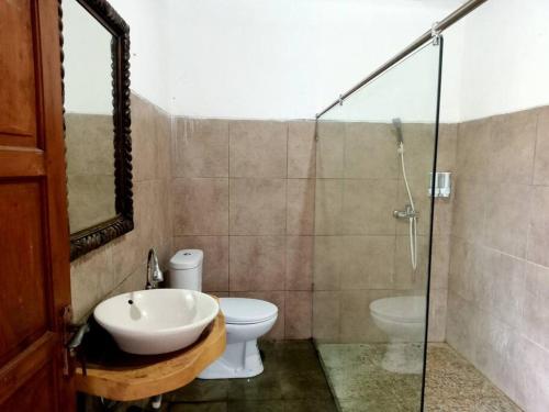 een badkamer met een toilet, een wastafel en een douche bij Tropical House Beach Bungalow in Kesembu