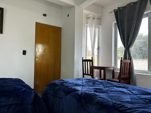 a bedroom with a bed and two chairs and a window at Virginia hotel in La Quiaca