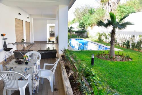 un patio con mesa, sillas y piscina en Luxurious Apt with Pool&Sea View en Pont Blondin