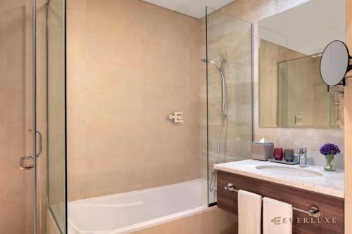 a bathroom with a shower and a tub and a sink at Everluxe Palm Views 3 Bedroom in Dubai