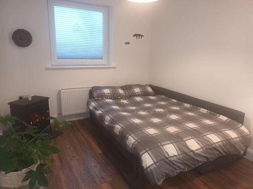1 dormitorio con 1 cama con manta a cuadros en Connemara Lake View Apartment, en Camus Eighter