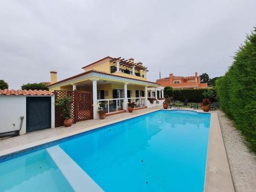 une grande piscine en face d'une maison dans l'établissement Casa Da Luz Villa - Praia D'El Rey Golf Resort, à Casal da Lagoa Seca