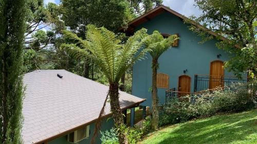 uma casa azul com palmeiras em frente em POUSADA GRESSONEY MOUNTAIN em Monte Verde