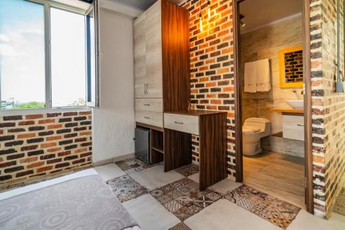 a bathroom with a brick wall and a toilet at Casa del Sol in Villavicencio