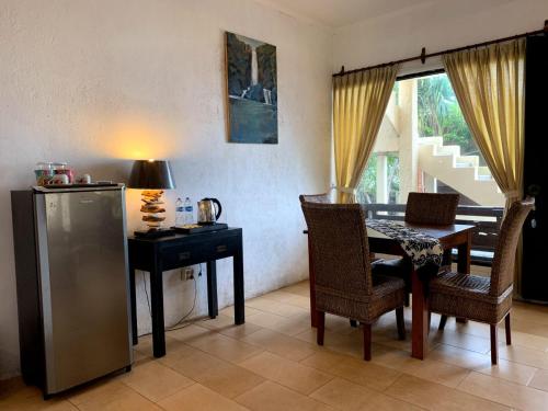 - une salle à manger avec une table, une table et des chaises dans l'établissement Tropical House Beach Bungalow, à Kesembu