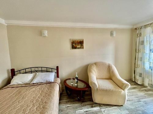 a bedroom with a bed and a chair and a table at Apartment Budivelnykiv 22/11 in Kyiv