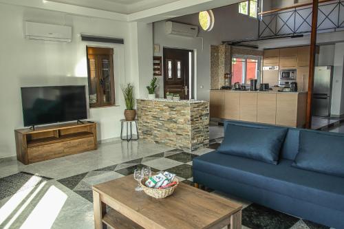 a living room with a blue couch and a tv at Angels beach house in Rhodes Town
