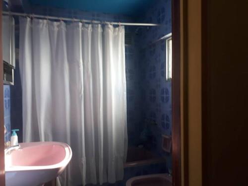 ein Badezimmer mit einem weißen Duschvorhang und einem Waschbecken in der Unterkunft LUMINOSO FUNCIONAL. UBICACION Y VISTA INMEJORABLES in San Carlos de Bariloche