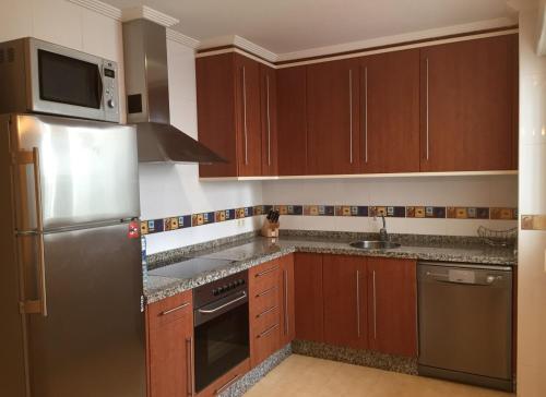 uma cozinha com armários de madeira e um frigorífico de aço inoxidável em Tranquilo y acogedor piso con encanto em Vegadeo