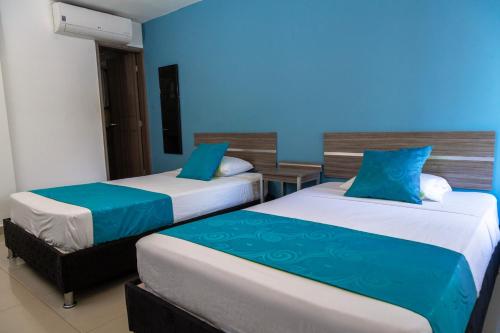 two beds in a room with blue walls at Casa del Sol in Villavicencio