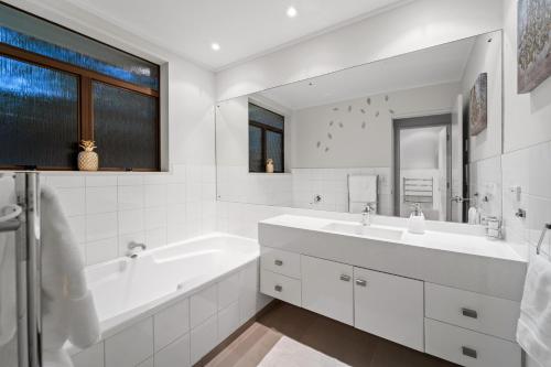 uma casa de banho branca com uma banheira e um lavatório em Entire house with pool, spa em Auckland