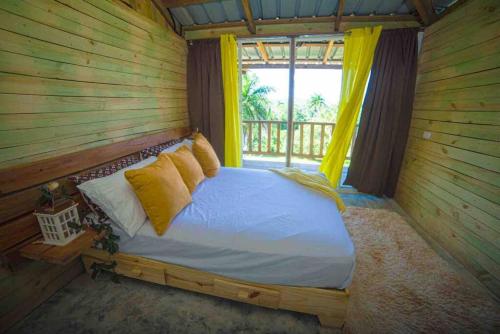 Ce lit se trouve dans une chambre en bois dotée d'une fenêtre. dans l'établissement Vista al Valle, à San Felipe de Puerto Plata