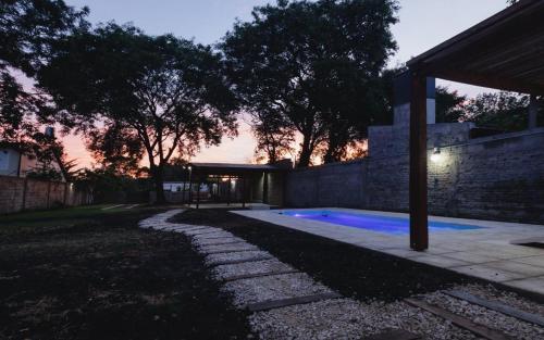un patio trasero con piscina al atardecer en LA CASA DE AL LADO en Mercedes