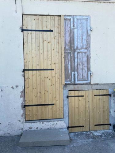 two wooden doors on a building with a window at Jolie studio in Saint-Pourçain-sur-Sioule