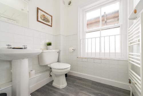 a white bathroom with a toilet and a sink at Bosuns Chair in Lymington