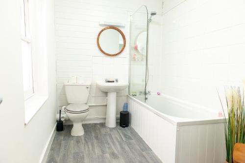 a white bathroom with a toilet and a sink at Bosuns Chair in Lymington