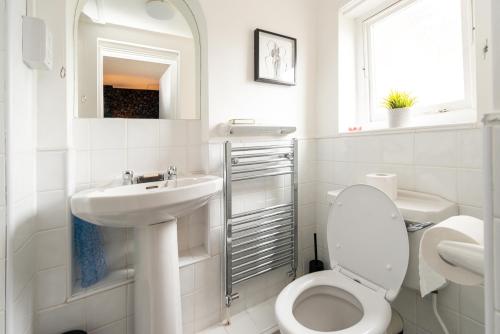 a white bathroom with a toilet and a sink at Bosuns Chair in Lymington