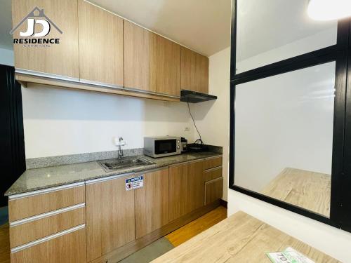 a kitchen with a sink and a microwave on a counter at JD Residence - 1 Bedroom Unit in Davao City