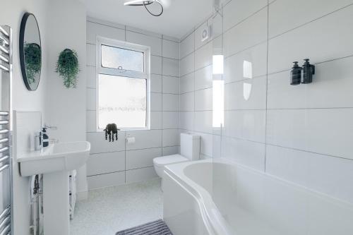 a white bathroom with a tub and a sink at Inspira Stays - Modern Stylish 2 Bedroom House - Free Parking - Wi-Fi - Monthly Discount in Leicester