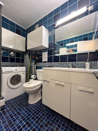 une salle de bains bleue et blanche avec des toilettes et un lave-linge. dans l'établissement Le Roi Soleil : Apt 2 Prs vue mer, 300 m plages, à Antibes