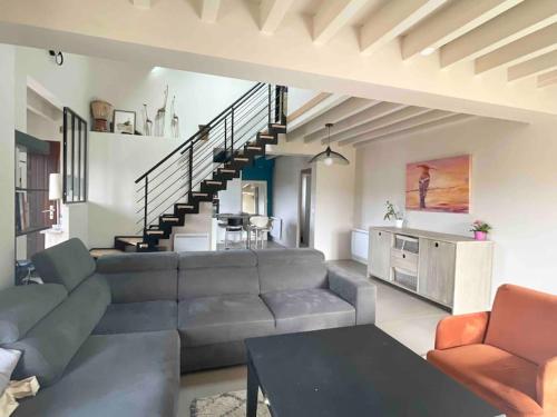 een woonkamer met een bank en een trap bij Maison entre lacs et fôrets in Montréal La Cluse