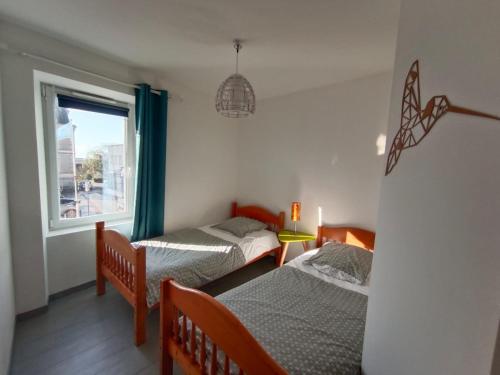 deux lits dans une chambre avec une fenêtre dans l'établissement La Patelle, à Barneville-Carteret