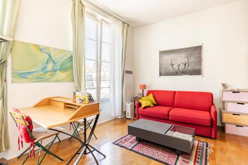 un salon avec un canapé rouge et une table dans l'établissement Appartement de charme - Haut Marais - Paris Centre, à Paris