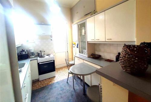 a small kitchen with white cabinets and a table at Mina's Veranda 90 sqm in Patra