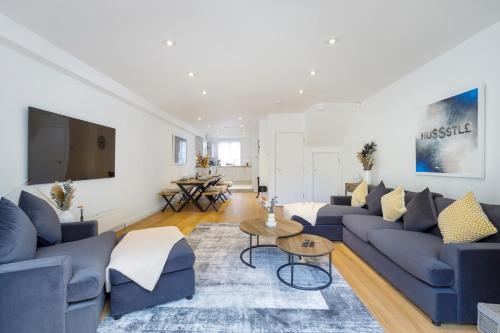 a living room with blue couches and a tv at Luxury 5 Bedroom House By The Sea in Brighton & Hove