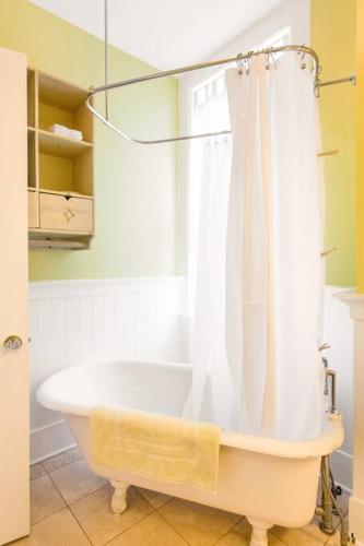 a bath tub with a shower curtain in a bathroom at iKlektik House // BlueJay in Chicago